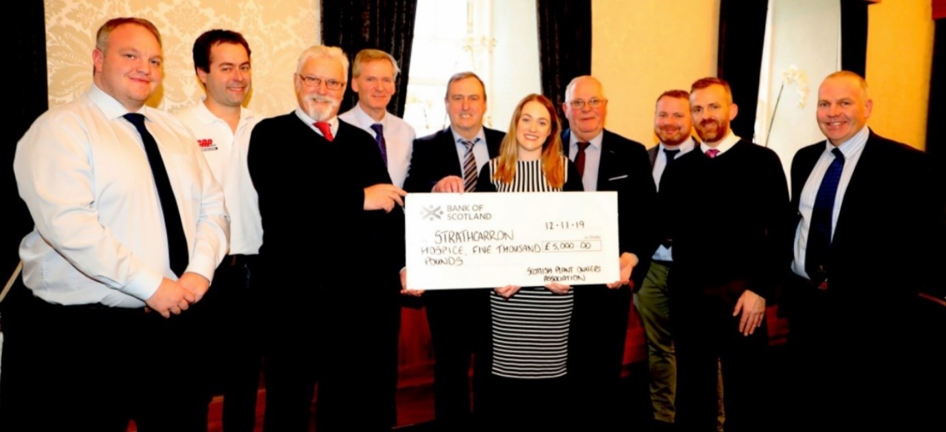 Above the SPOA Committee hands over a cheque for £5,000 raised at the annual dinner dance to Strathcarron Hospice. Brian (third from the left) proudly holding the cheque